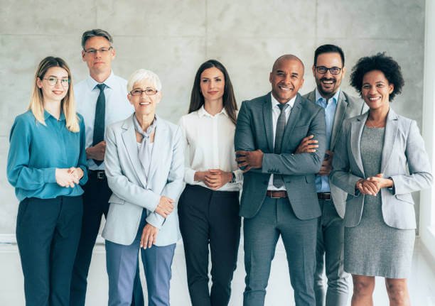 Multi-ethnic group of business persons standing in modern office and looking at camera